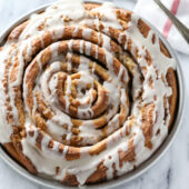 Giant fluffy homemade cinnamon roll cake with a sweet vanilla glaze. Recipe from @bakedbyrachel