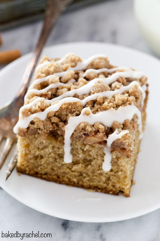Slice of apple coffee cake with icing drizzle on a white plate