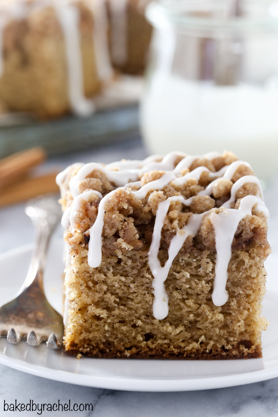Slice of apple coffee cake with icing drizzle on a white plate