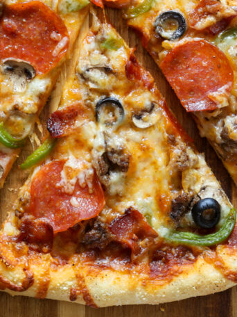 Easy homemade thin crust three cheese supreme pizza recipe from @bakedbyrachel This flavor packed pizza is topped off with a variety of classic pizza topping vegetables and meat, from bacon to peppers, mushrooms and more! A perfect addition to any pizza night or game day menu!